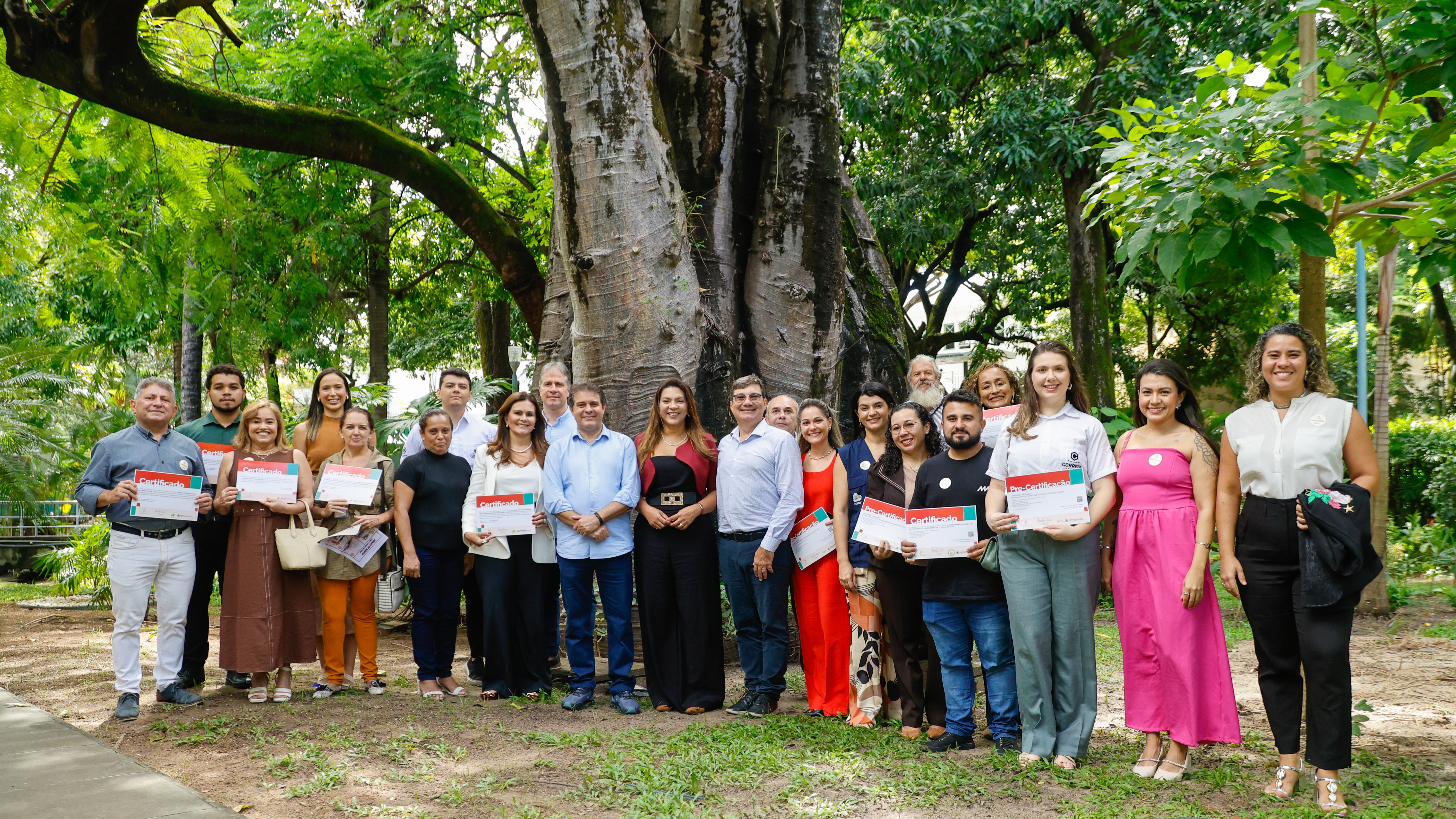 grupo de pessoas posa em frente a uma árvore baobá no jardim do paço municipal